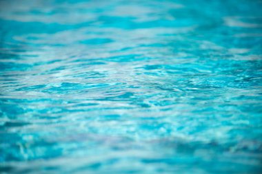 Yüzme havuzundaki mavi suyun arka planında güneş yansıması, havuzda dalgalı su dalgaları. Temiz su arkaplanı