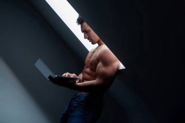Laptop kullanan seksi adam. Yatakta dizüstü bilgisayarlı Latin bir adam. Kaslı vücudu ve dizüstü bilgisayarı olan seksi bir genç. Genç adam yatmadan önce dizüstü bilgisayar kullanıyor.