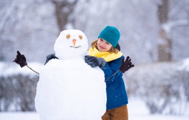 Mutlu Çocuk kışın kardan adam için kartopu yapıyor. Çocuk karda oynuyor. Açık havada aktif kış oyunları. Çocuk karla oynarken eğleniyor. Çocuklar için açık havada kış tatili. Güneşli kış gününde çocuk oyunu