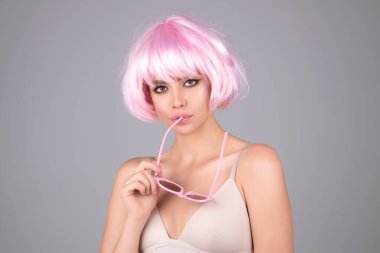 Pembe peruklu komik kız. Mükemmel ciltli, doğal makyajlı ve güzel bir yüzü olan genç bir kadın. Stüdyo arka planında çıplak omuzlu bir kadın portresi. Güzellik salonu için doğal kozmetik reklamı.