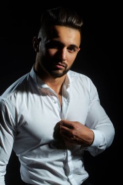 Moda gömleği. Beyaz gömlekli seksi çıplak vücutlu seksi bir manken. Siyah arka planda düğmesiz beyaz gömlekli seksi bir adam. Seksi bir adam. Açık tişörtlü adam.