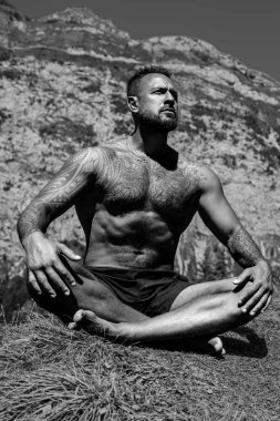 Hispanik Adam dışarıda otların içinde meditasyon yapıyor. Sporcu şehir parkında yoga yaparken asana meditasyonu yapıyor. Atletik erkek meditasyonu, rahatlama, sağlıklı yaşam tarzı kavramı. Açık havada meditasyon.