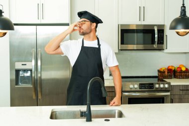Mutfakta yemek pişiren aşçı. Ev mutfağında mükemmel yemek işareti olan şefler. Aşçı adam yemek yapıyor. Lezzet işareti yapıyor. Aşçılar mutfakta şapka ve önlükle yemek pişirir.