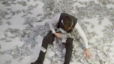 Sakallı adam para banknotları içinde yatıyor. Para geçmişi olan bir iş adamı. İşadamı bir yığın parayı israf ediyor, kumarhane piyangosunu kazanıyor, 100 dolar kazanıyor. Para ve zengin konsept