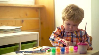Anaokulu çocukları. Küçük şirin bir çocuk resmi ve çizimi. Pastel boyalı ve kağıda çizim yapan bir çocuk. Yaratıcı düşünce ve çocukların sanatsal kavramları. Boyalı fırça ve suluboya çocuk resimleri