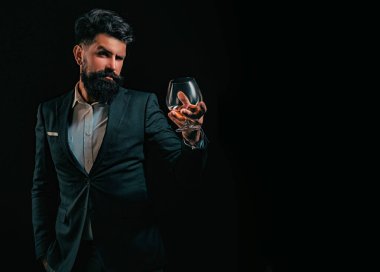 Sakallı adam cam brendi tutuyor. Yakışıklı sakallı iş adamı pahalı konyak içiyor. Sommelier adam