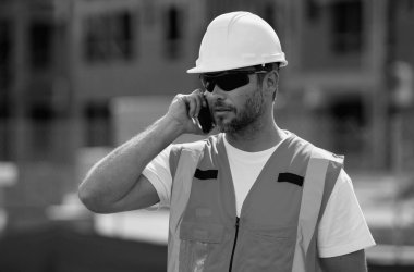 Çalışanlar telefon kullanıyor, inşaatçılar işe ara veriyor. Cep telefonu olan bir mimar. Mühendis üniformalı bir mühendis. Yeni bir ev inşa etmeye hazır inşaatçının portresi