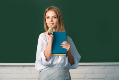 Sınıfta tahtadan arkaplanı olan genç, sarışın bir üniversite öğrencisinin portresi.