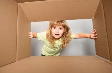 Neşeli şirin çocuk hediyesini açıyor. Karton kutular, paketler. Teslimat hizmeti konsepti. Çocuklar şaşırmış yüz ifadeleri