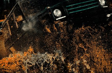 Lastikler yarışa hazırlanıyor. Jeep bir su birikintisine çarptı ve bir toz püskürtüsü aldı. Çamur ve su off-road yarışında sıçrıyor