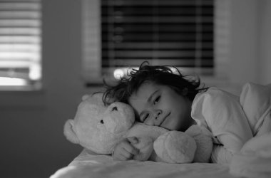 Oyuncak ayılı çocuk gece kayışından hoşlanıyor. Çocuk uyuyor. Uykulu çocuk yatakta. Küçük çocuk yatakta. Çocukluk konsepti. Uyumak için favori oyuncak