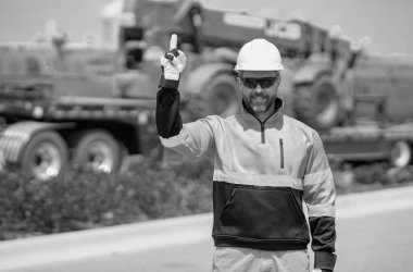 İnşaat işçisi endüstriyel alanda kazıcı ile çalışıyor. Kask takan, buldozerli bir işçi. Mühendis, inşaat firmasında çalışıyor. Traktörlü kazı ustabaşı