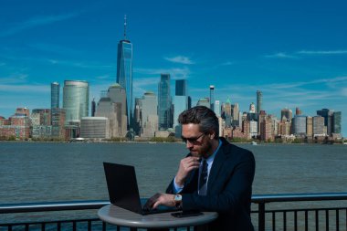 New York 'ta dışarıda dizüstü bilgisayar kullanan bir iş adamı. İş dünyası Amerikan başarısı. Amerikan iş rüyası. Manhattan yakınlarında takım elbiseli Amerikalı iş adamları. ABD 'de online iş