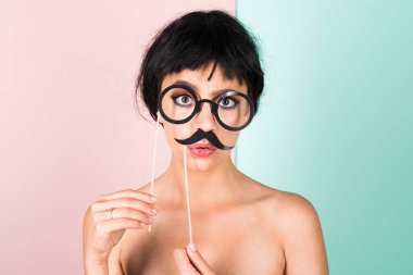 Siyah peruklu genç bir kadın sahte bıyığı pozitif ve mutlu yapıyor. Komik kız gülüşü. Genç transseksüel kadın. Komik kadın suratı. Çekici, suratını buruşturan komik kızın portresi. Duygu kızı.