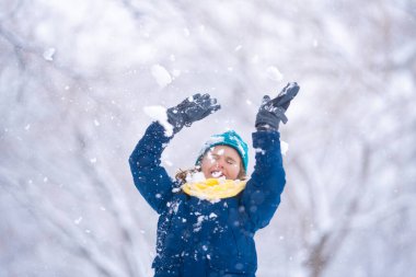 Karda oynayan çocuk. Kış çocuğu, açık hava portresi. Çocuk karda oynuyor. Kar parkında çocuk oyunu. Kış çocuğu suratı. Karda mutlu bir genç çocuk. Kış çocukları aktivitesi