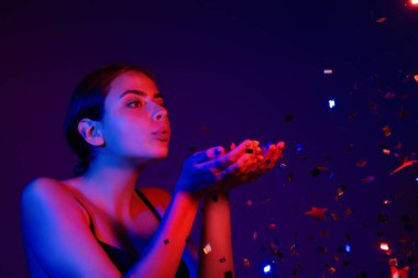 Doğum günün kutlu olsun. Konfeti üfleyen kızın stüdyo portresi. Doğum gününde ya da sevgilisinde konfeti olan güzel kız. Seksi model doğum gününde konfeti üflüyor. Doğum günü esprilerini kutlayan şehvetli kadın.