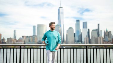 Olgun bir sporcu, New York 'ta aktif yaşam tarzının tadını çıkarıyor. Adam esneme egzersizi yapıyor, Manhattan yakınlarında antrenmana hazırlanıyor. Sportif formda bir adam. 40 'lı yaşlarda spor giysileri giyiyor.