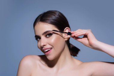 Eyebrow shaping, woman combs eyebrows with a brus. Eyebrow line. Makeup and cosmetology concept. Female model with long eyelashes and thick eyebrows. Perfect shaped brow