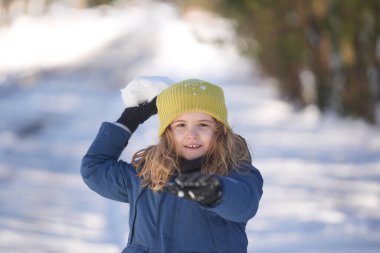 İlk kar yağışında çocuk dışarıda karla oynuyor. Çocuklar için kış aktiviteleri. Çocuk kartopu savaşından zevk alıyor. Karlı ormanda kartopu oynayan bir çocuk. Kardan kaçan komik çocuk. Kış eğlencesi