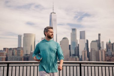 Spor salonundaki adam Manhattan yakınlarında egzersiz yapıyor. Sağlıklı fitness yaşam tarzı. Aktif kıdemli adam dışarıda fitness egzersizi yapıyor. Emeklilikten sonra spor. Olgun emekli sporcu esneme egzersizleri yapıyor.