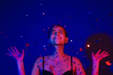 Doğum günün kutlu olsun. Konfeti üfleyen güzel bir kızın stüdyo portresi. Doğum gününde ya da sevgilisinde güzel bir genç bayanın portresi. Güzellik mankeni doğum gününde ışıldar. Doğum gününü kutlayan şehvetli kadın.