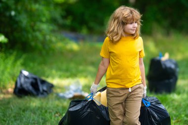Çevre plastik kirliliği. Ormanda çöp toplayan ve elinde çöp torbası tutan gönüllü bir çocuk. Çevresel koruma. Çevre aktivisti. Çevre koruma ve atık kirliliği
