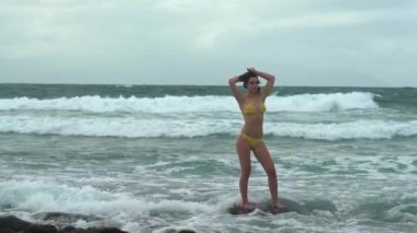 Yaz tatilinde tropik plajda dinlenen seksi kadın. Okyanus dalgalarının kıyısında bikini mayo giymiş genç bir kadın. Tatil, seyahat, rahatlama konsepti. Okyanustaki seksi kadın