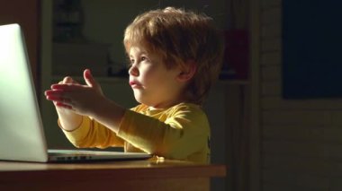 Bilgisayarlı bebek. Evde dizüstü bilgisayarla çalışan sarışın bir bebek. Küçük çocuk dizüstü bilgisayarını kullanıyor. Sevimli bebek bilgisayarı. Bilgisayardaki küçük çocuk. Bilgisayar kullanan bir çocuk. Bebek dizüstü bilgisayarın önünde şaşırdı.