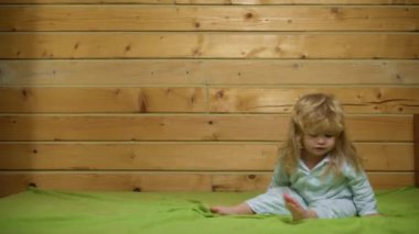 Pijamalı bebek gülüyor ve eve yatağa atlıyor. Çocukluk, günaydın. Bebek yatakta zıplıyor, evde eğleniyor. Çocuk zıplayarak ve yatakta oynayarak eğleniyor. Yatak odasında bebek oyunu