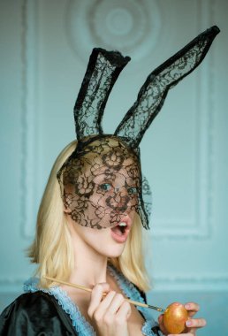 Tavşan kulağı takan ve renkli bir Paskalya yumurtası tutan çekici genç bir kadın. Güzel, şehvetli bir kadının moda portresi ve çok şehvetli görünüyor. Eğleniyorum. Kadın Paskalyası