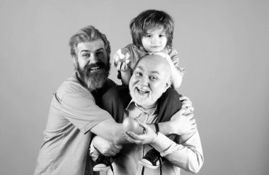 Baba, oğul ve büyükbaba mutlu bir aile. Mutlu yıllar, çok nesilli erkekler. Büyükbaba baba baba ve çocuk torun sarılıyor ve gülümsüyor.