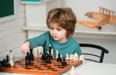 Küçük çocuk satranç oynuyor. Öğrenci çocuk satranç oyunundaki bir sonraki hamlesini düşünüyor. Akıllı çocuklar.