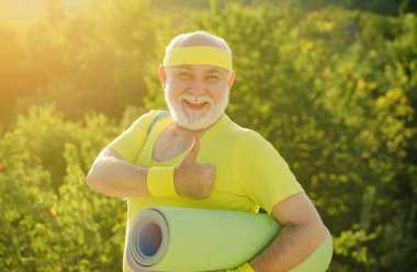 Spor Mutlu aktif yaşlı adam egzersiz paspası tutuyor. Fitness yoga halıları olan yaşlı bir adam. Yaşlı sporcular için enerjiktir. Spor gibi.