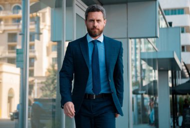 Yönetici işadamı. Modern ofis yakınlarında takım elbiseli bir CEO portresi. Şirket binasının önünde duran mutlu lider.