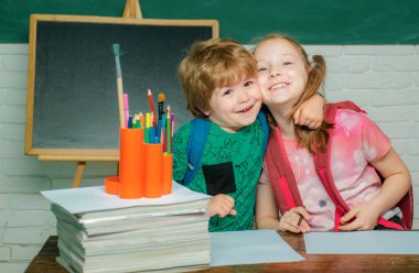 Okula geri dön. Okul malzemeleri ile masa nın yanında mutlu yüz ifadesi ile kız ve erkek