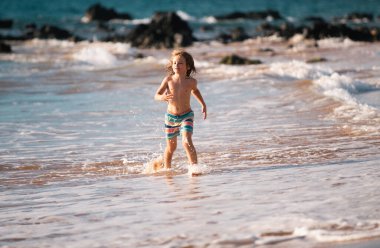 Sahildeki çocuk. Okyanusta oynayan küçük bir çocuk. Denizde tatiller. Dalgalar içindeki çocuk