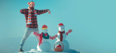 Heyecanlı adam ve kardan adam. Kışın arka planda kardan adam olan harika bir adam. Kış bayrağı için kardan adam. Noel ve yeni yıl kar konsepti, kış mevsimi