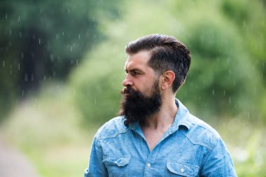 Yağmur altındaki yakışıklı adam. Sonbahar yağmurlu hava konsepti. Su geçirmez giysi