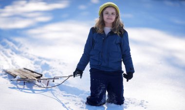 Çocuk kış şapkasıyla karda oynuyor. Sıcak giysili mutlu çocuk kar yağarken eğleniyor. Karlı parkta oynayan bir çocuk. İlk kar yağışında çocuk dışarıda karla oynuyor. Çocuklar için kış aktiviteleri