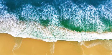 Kumsal havası, güzel kumlu bir kumsal manzarası. Yaz deniz dalgalarının en üst görüntüsü. Güneşli bir günde mavi deniz suyu. İHA 'dan hava görüntüsü. İnanılmaz tropikal doğa geçmişi. Sakin deniz dalgaları