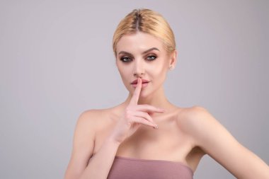 Utangaç sinsi kadın. Stüdyonun arka planında izole edilmiş şirin bir kızın sessiz jesti. Genç bir kadın sessiz olmak istiyor, parmakları dudaklarında. Sessizlik ve gizli konsept
