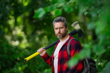 Ormanda baltası olan çalışkan bir adam. Büyük baltası olan sakallı bir oduncu. Ekose gömlekli vahşi sakallı bir adamın portresi bir balta tutuyor. Erkek güzelliği ve erkeklik