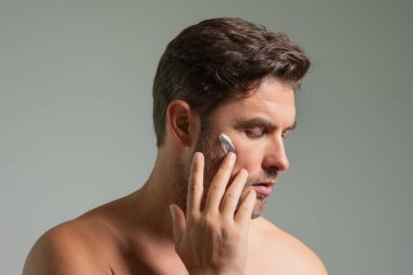 Yüzünde krema olan adam. Temiz ciltli bir güzellik uzmanı. Güzellik uzmanı cilt bakımı. Kozmetik ve kaplıca. Erkek kozmetik ürünleri. Yüz bakımı cilt bakımı ve güzellik kavramları. Yumuşak tenli yakışıklı bir adam.