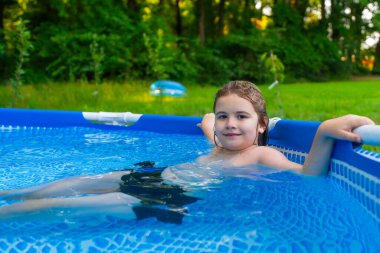 Evde çocuk havuzunda oynayan bir çocuk. Çocuklar bahçedeki havuzda yüzer ve su sıçratır. Çocuklar yaz güneşli bir günde evlerinin bahçesinde şişme havuzda yüzerler. Çocuklar evde havuz yüzüyor.