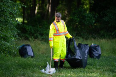 Küresel çevre kirliliği. Bir gönüllü dışarıda plastik çöp topluyor. Çevre koruma kavramı. Adam çöpleri çöp torbasına koyuyor. Çevre gönüllüsü. Çevre kirliliği