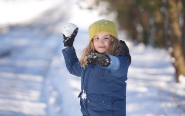 İlk kar yağışında çocuk dışarıda karla oynuyor. Çocuklar için kış aktiviteleri. Çocuk kartopu savaşından zevk alıyor. Karlı ormanda kartopu oynayan bir çocuk. Kardan kaçan komik çocuk. Kış eğlencesi