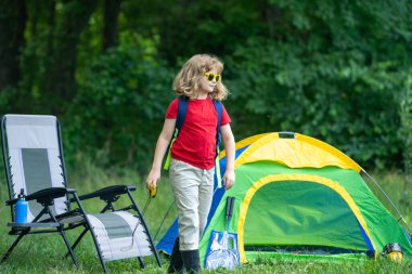 Doğayı keşfeden bir çocuk. Ormanda yürüyüş yapan bir çocuk. Kamp yapan çocuk. Sırt çantalı çocuk doğa yolunda. Küçük gezgin. Kampta doğayı keşfeden çocuk
