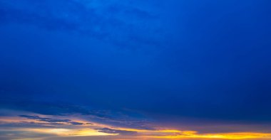 Gündoğumu arka planı. Dramatik görkemli gün batımı. Gökyüzü bulutlu ve arka planda gökyüzü aydınlığı var. Farklı şekillerde bulutlarla gün doğumu. Sakin gündoğumu gökyüzü ve bulutlar arasından güneş.