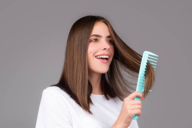 Tarakla saçlarını tarayan bir kadın. Saç fırçasıyla uzun, sağlıklı saçları tarayan bir kız. Saç bakımı güzellik konsepti. Saç fırçalama
