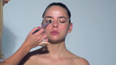 Genç ve seksi bir kadının moda makyajı. Yüzünüzü kapatın, makyaj yapın, rimel sürün. Makyaj sanatçısı cilt, kızartıcı ve pudra kullanıyor. Güzel kadın yüzü. Mükemmel ciltli, şehvetli bir kız.